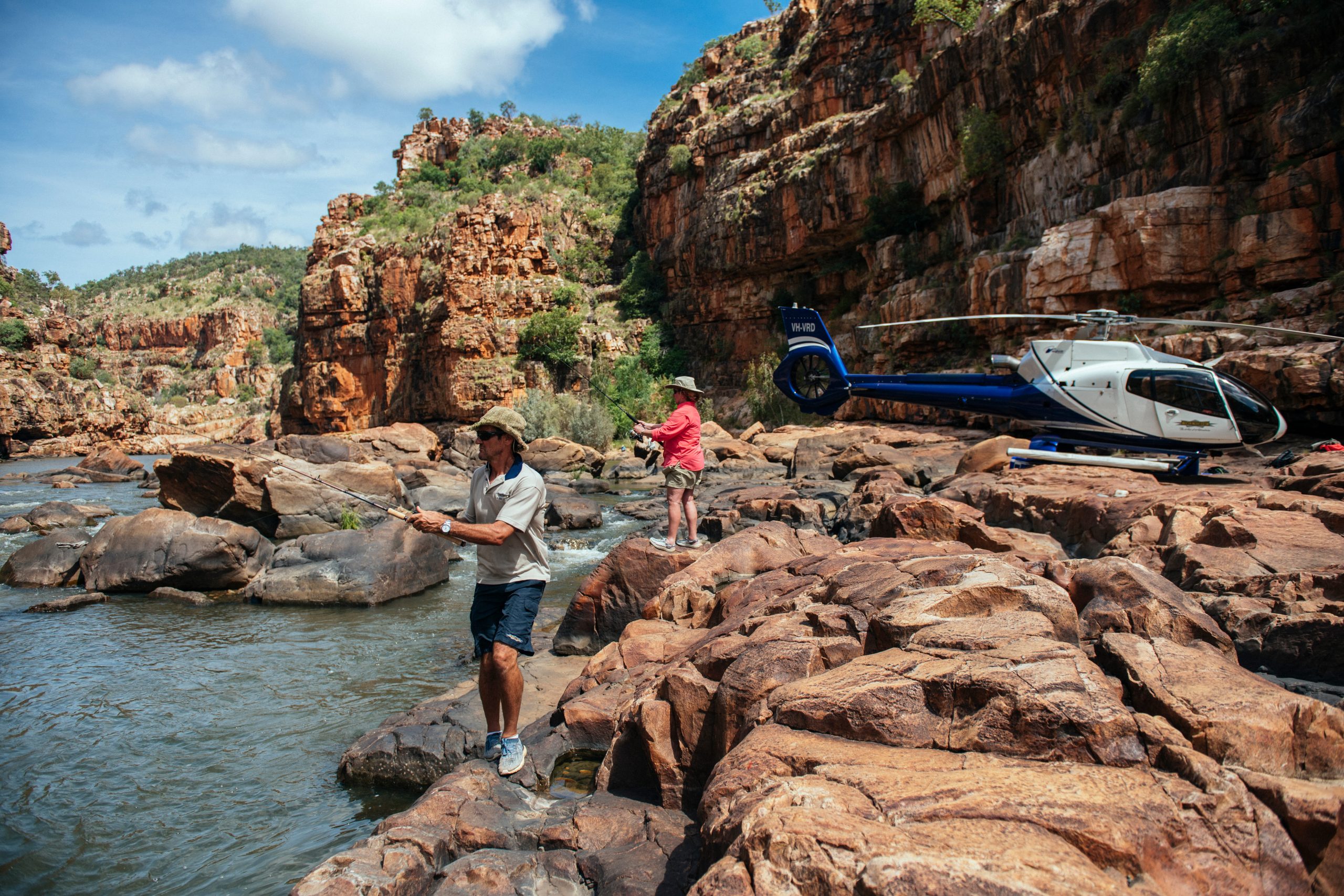 Two guests enjoy heli-fishing beside a rugged freshwater gorge in the Kimberley during a TRUE NORTH expedition cruise. 