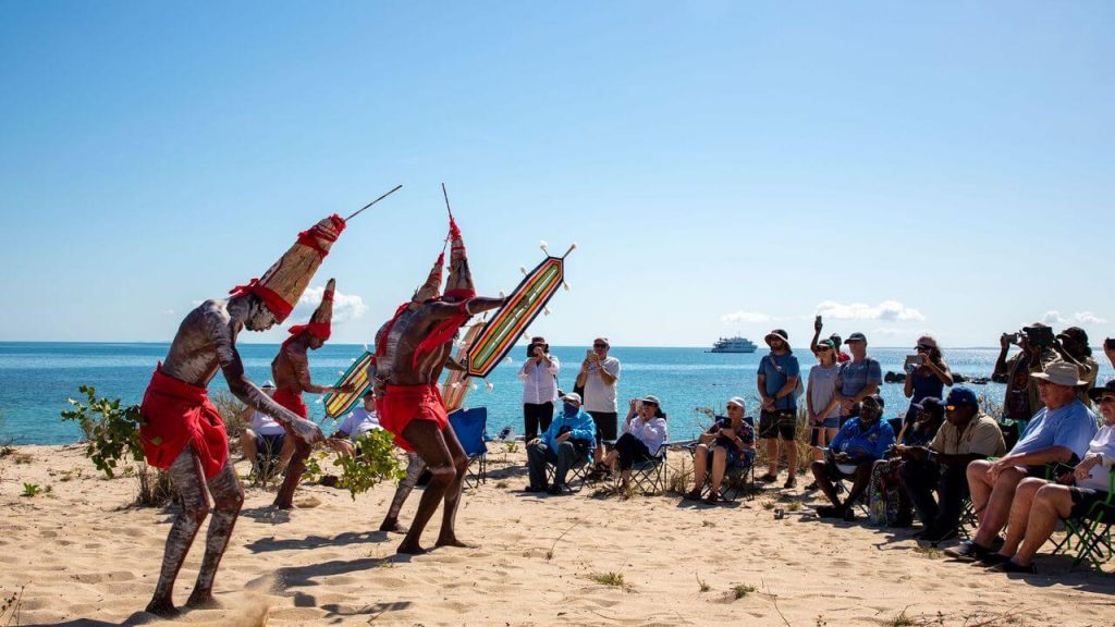 True North cruise guests watching traditional cultural dance on beach