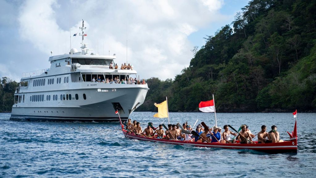 True North luxury cruise ship and traditional canoe in scenic bay