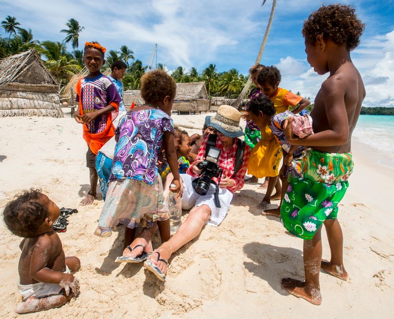 Informative expedition: photographer engaging with children on tropical beach