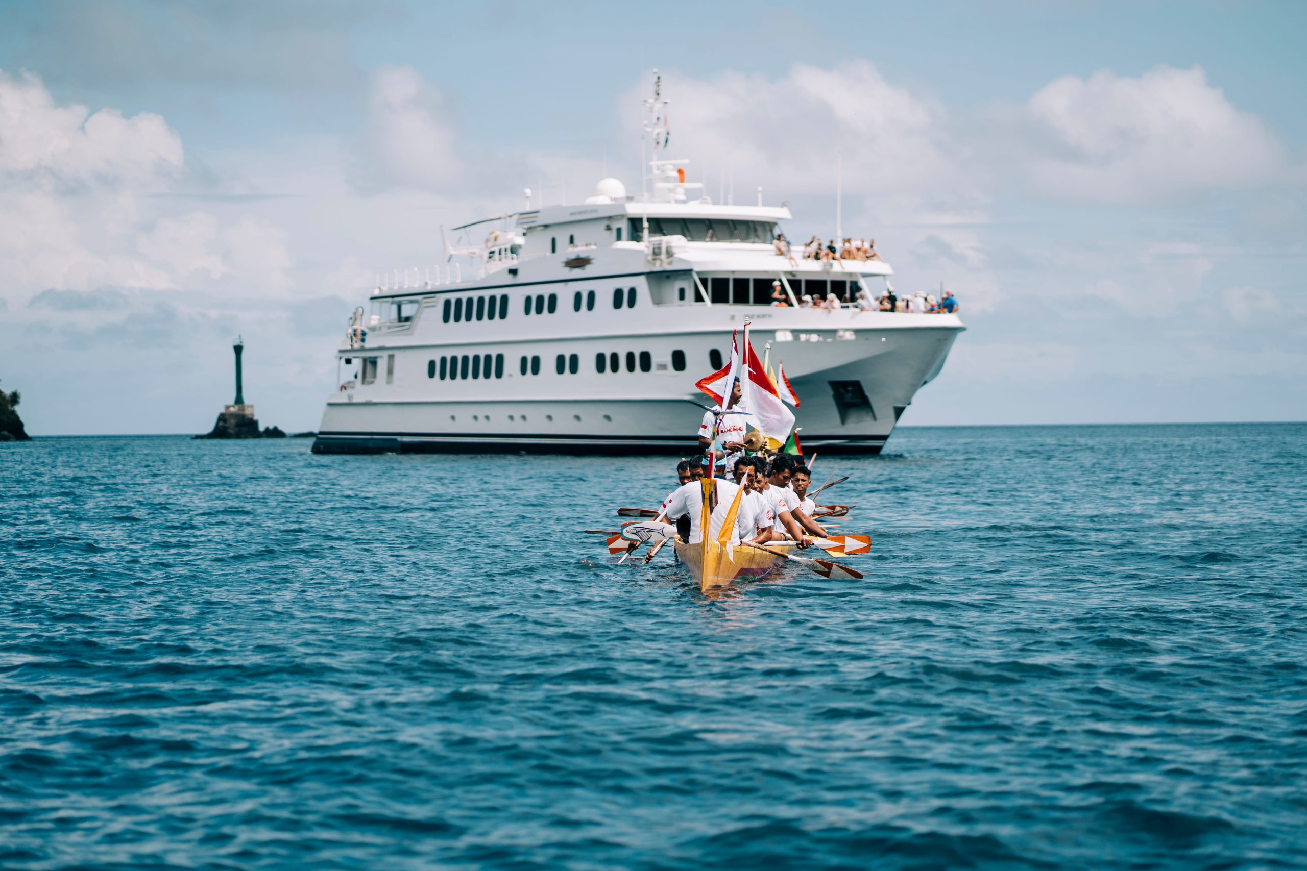 Traditional canoes lead the True North expedition vessel into a Raja Ampat harbour