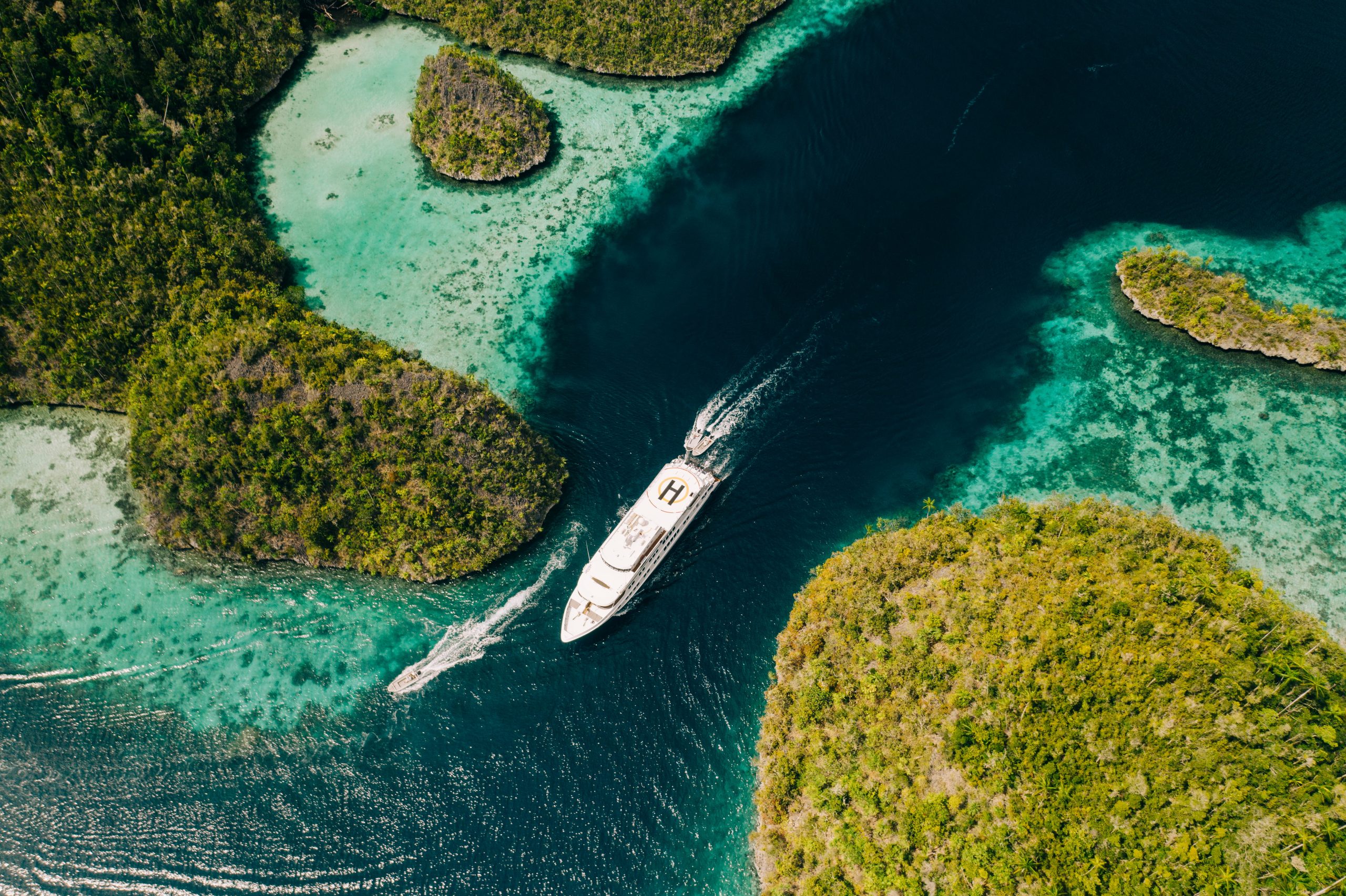 Aerial view of the True North expedition yacht cruising through narrow turquoise channels