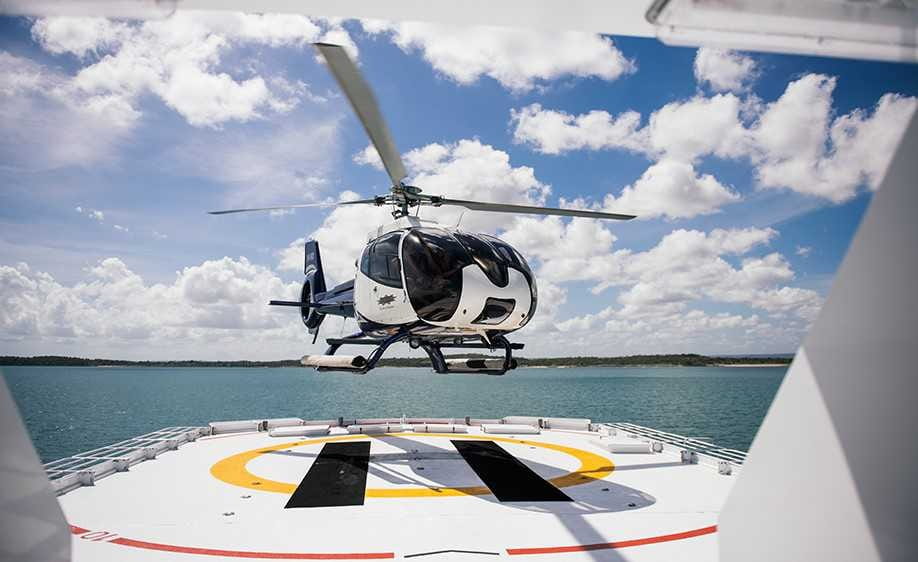 Helicopter landing on True North helideck showcases cruise ship vs yacht adventure capabilities