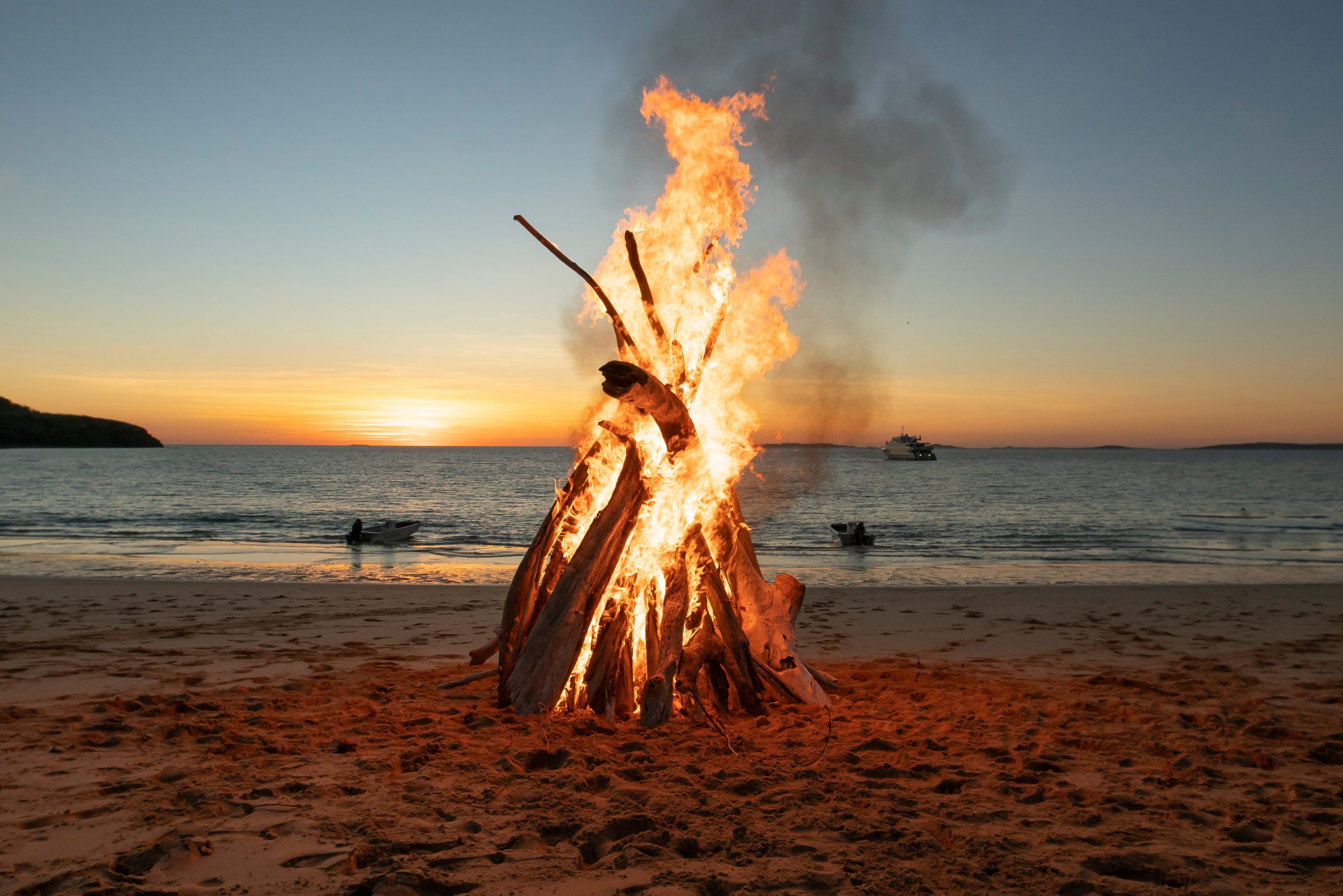 Beach bonfire burning at sunset along a remote coastline