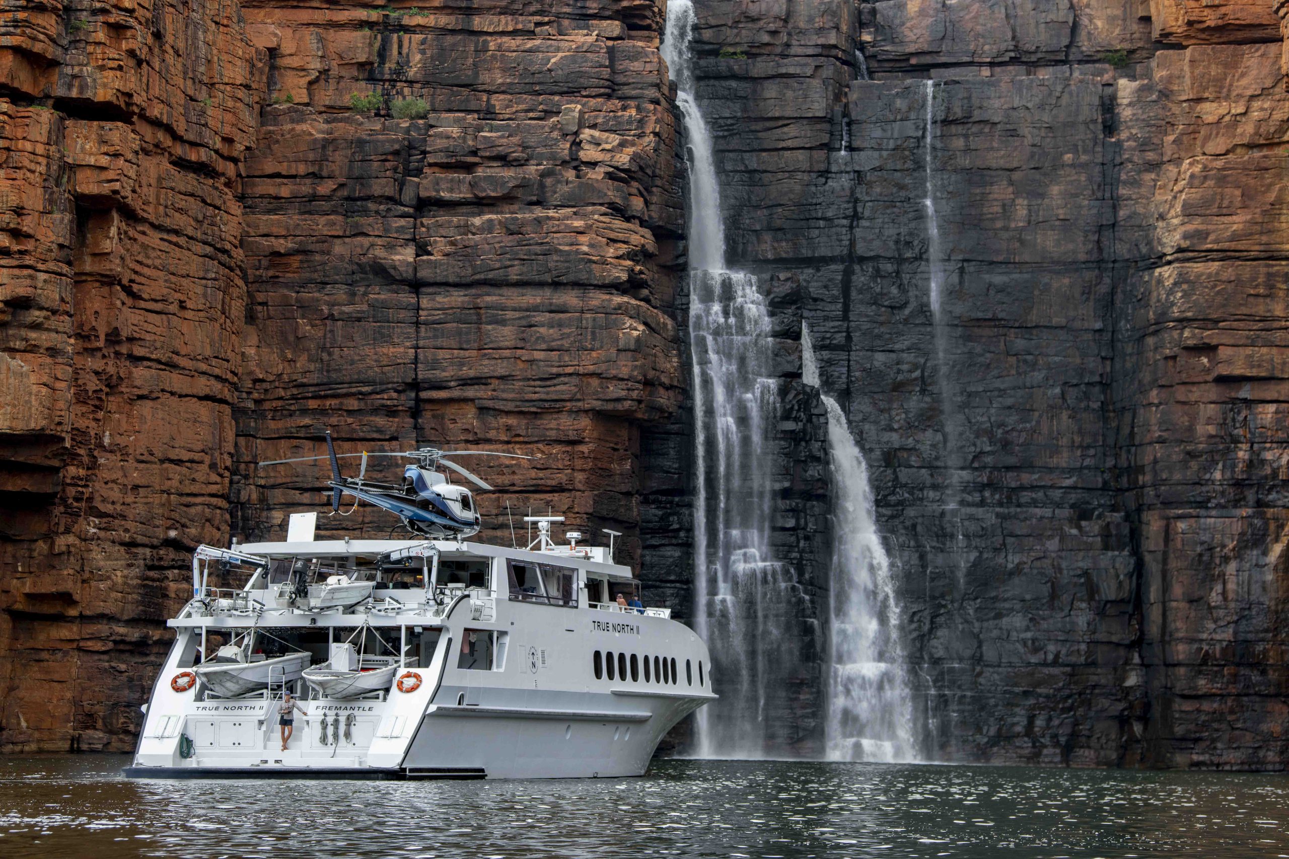 True North luxury cruise beneath King George Falls in the Kimberley with guests on the bow
