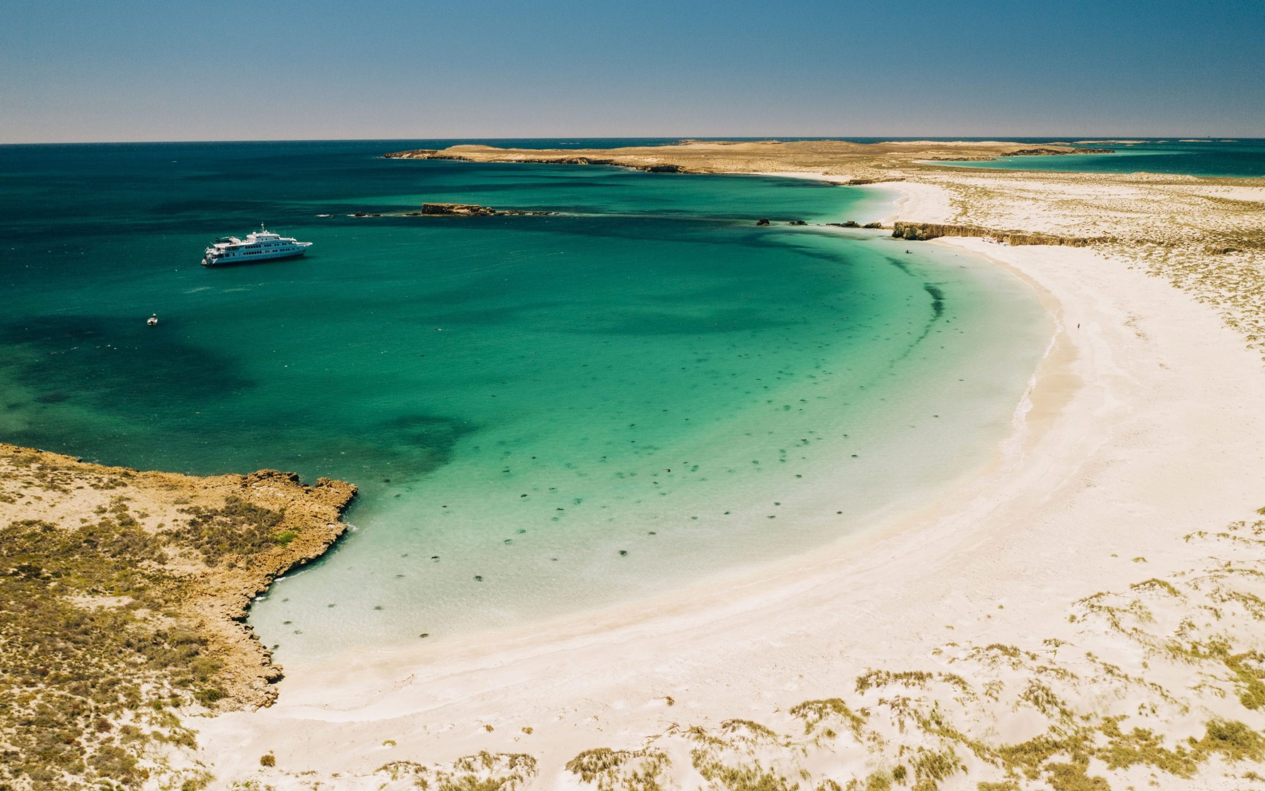 True North luxury cruise anchored off a remote Australian coast beach with turquoise water and white sand