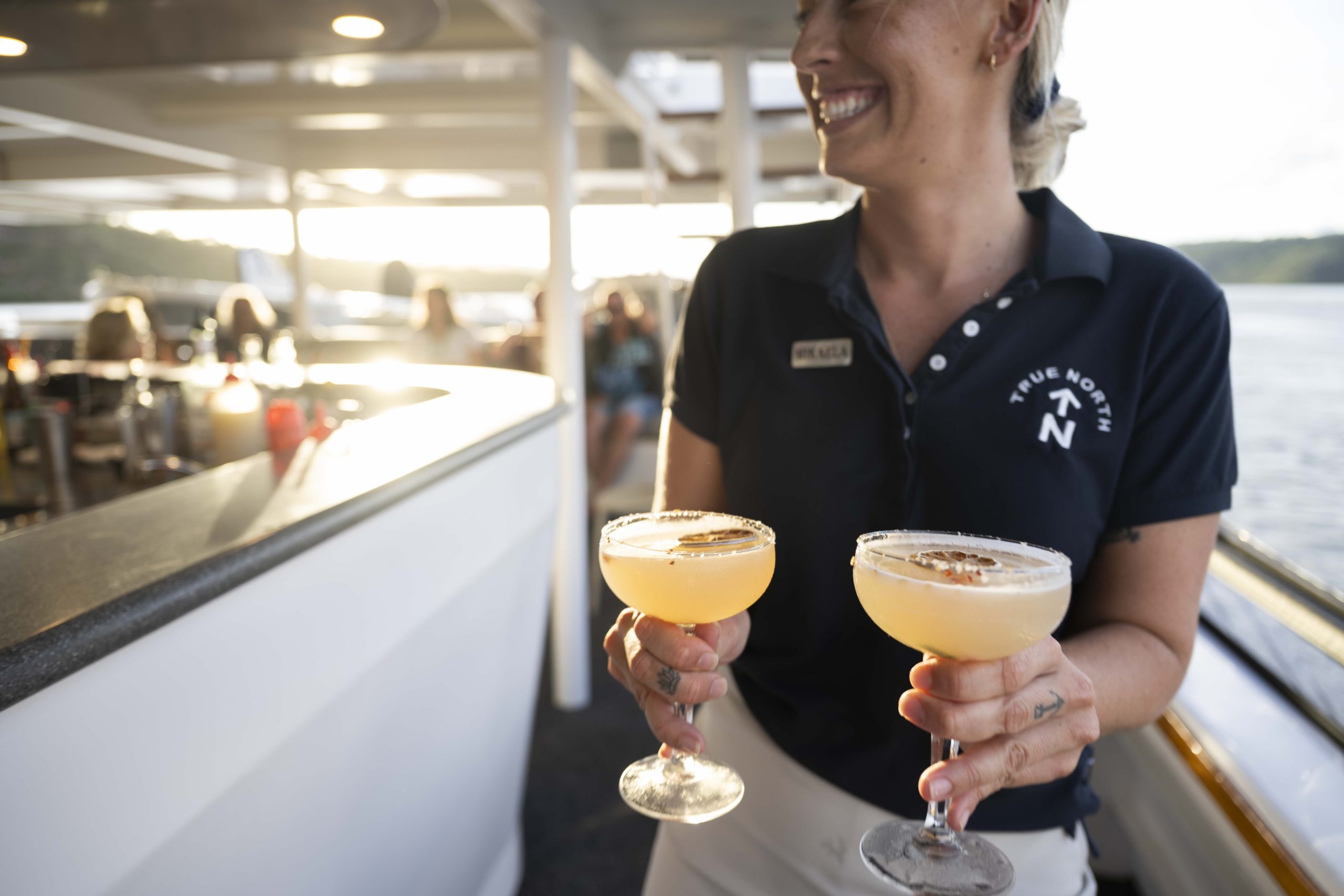 True North staff member serving cocktails on deck during sunset cruise in the Kimberley
